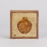 Leach Pottery; a square stoneware tile covered in oatmeal glaze and decorated with a pot, painted