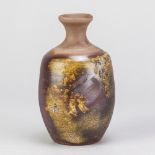 A stoneware Bizen style sake bottle covered in iron rich glaze with mottled green decoration,
