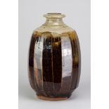 PHIL ROGERS (1951-2020); a large stoneware cut sided bottle covered in tenmoku breaking to kaki
