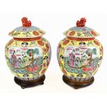 A pair of 20th century Chinese Famille Jaune vases and covers, decorated with scenes of figures at