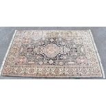An Eastern style part silk rug with elephant foot decoration to the centre and outer border on a