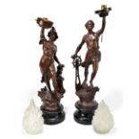 A pair of spelter table lamps, modelled as a man and a woman, both with glass shades upon wooden