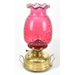 VERITAS; a large brass oil lamp with dimpled cranberry glass shade and clear glass chimney, height