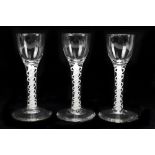 Three wine glasses with fluted bowls raised on double opaque air twist stems terminating on