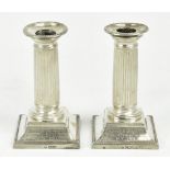 A pair of Edwardian hallmarked silver dwarf candlesticks, with fluted columns and swept bases,