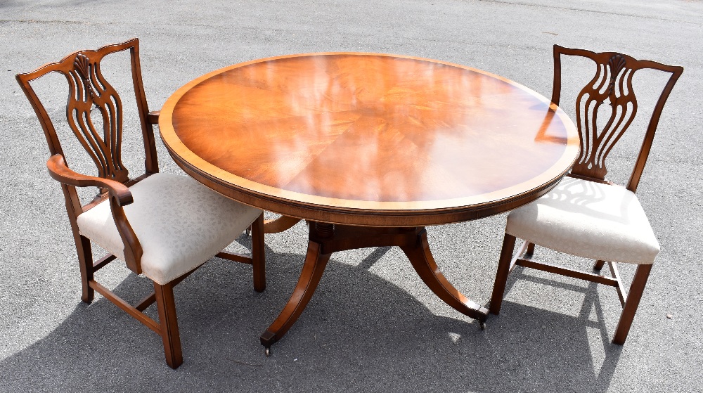 A reproduction mahogany dining table, the circular top on four columns terminating on four sabre