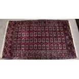 A Bokhara type rug with elephant foot decoration to the centre inside a checkered border on a