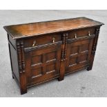 A 1920s oak sideboard with applied columns, and two drawers above a pair of panelled cupboard doors,