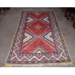 A Caucasian hand woven wool rug, worked with a central geometric field against a red ground, 315 x