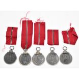 Five German WWII East medals, two fitted in original packaging, with one extra ribbon.