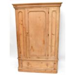 An old pine wardrobe with moulded cornice raised above the panelled door above a single base