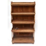 A modern pine freestanding waterfall bookcase with carved detail on scrolling supports, on bun feet,