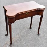 A George III mahogany fold over card table of shaped rectangular, on turned column supports,