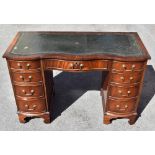 A reproduction mahogany veneered serpentine fronted kneehole desk, with green leather inset top