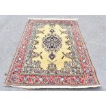 A Persian hand woven wool carpet, decorated with a central medallion against a pale green ground,