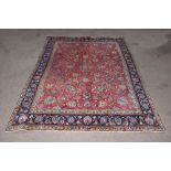 A Persian hand woven wool carpet worked with an allover floral design against a red ground, 320 x