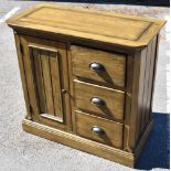 A modern oak side cabinet with single panelled door flanked to one side by  three drawers, on plinth
