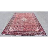 A Persian hand woven wool rug, decorated with a central medallion and allover floral design