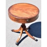 A reproduction mahogany drum coffee table with three drawers on turned column and four swept