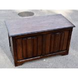 A reproduction oak effect blanket chest with linen fold detail to the front, on bracket feet,