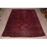 A Bokhara hand woven wool carpet, worked with eight geometric guls, 260 x 211cm.