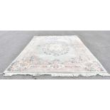 A large Chinese wool carpet decorated with a central floral medallion against a pale green ground,