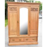 A walnut twin door wardrobe with moulded cornice above the central mirrored plate flanked by a