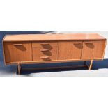 A mid-century teak sideboard with an arrangement of three drawers, two panelled doors and a pull-