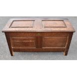 An 18th century oak coffer of rectangular form, with panelled top and front and block feet, width