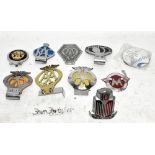 Nine vintage car badges, including three AA, a Wolseley Register and a Standard.