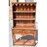 A reproduction oak dresser of small proportion, with boarded plate rack above two frieze drawers and