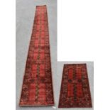 A machine woven wool runner of long proportions, with geometric detail against a red ground, 635cm x