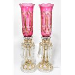 A pair of 20th century Bohemian ruby and clear glass lustre lamps, with storm shaped shades,