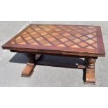 An early 20th century oak draw-leaf dining table with a checkered top, on carved pineapple supports,