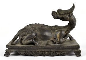 A late 19th/20th century Chinese bronze model of a kylin, the mythical beast modelled recumbent with