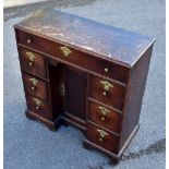 An 18th century oak seven drawer knee-hole desk of small size, with central recessed panel door,