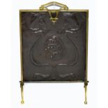 An Arts & Crafts brass framed fire screen with sheet copper central panel with embossed scrolling/