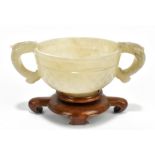 A Chinese carved and polished celadon jade twin handled cup, with central band of decoration to