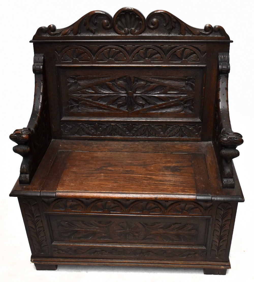 An early 20th century small carved oak settle with hinged seat, width 91cm, depth 44cm, height