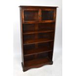 A 1930s oak bookcase with twin glazed upper doors above three fixed shelves to a plinth base, height