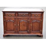 A reproduction oak dresser with three frieze drawers above three panel doors on bracket feet,