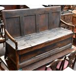 An 18th century oak settle with four panel back above a hinged seat, width 160cm.