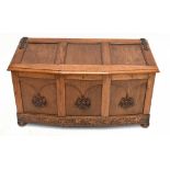 A 1950s carved oak blanket chest with panelled front, on bun feet.