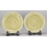 MIKE DODD (born 1943); a pair of stoneware plates covered in green ash glaze, impressed MJD marks,