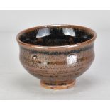 JIM MALONE (born 1946); a stoneware bowl covered in tenmoku breaking to kaki glaze with impressed