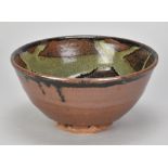 JIM MALONE (born 1946); a stoneware bowl covered in tenmoku breaking to kaki glaze with copper green