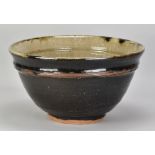 JIM MALONE (born 1946); a large deep stoneware bowl covered in tenmoku breaking to kaki glaze with