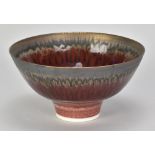PETER WILLS (born 1955); a porcelain bowl covered in copper red glaze with bronze running from the
