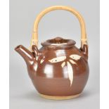 JIM MALONE (born 1946); a stoneware teapot with cane handle covered in kaki glaze with wax resist