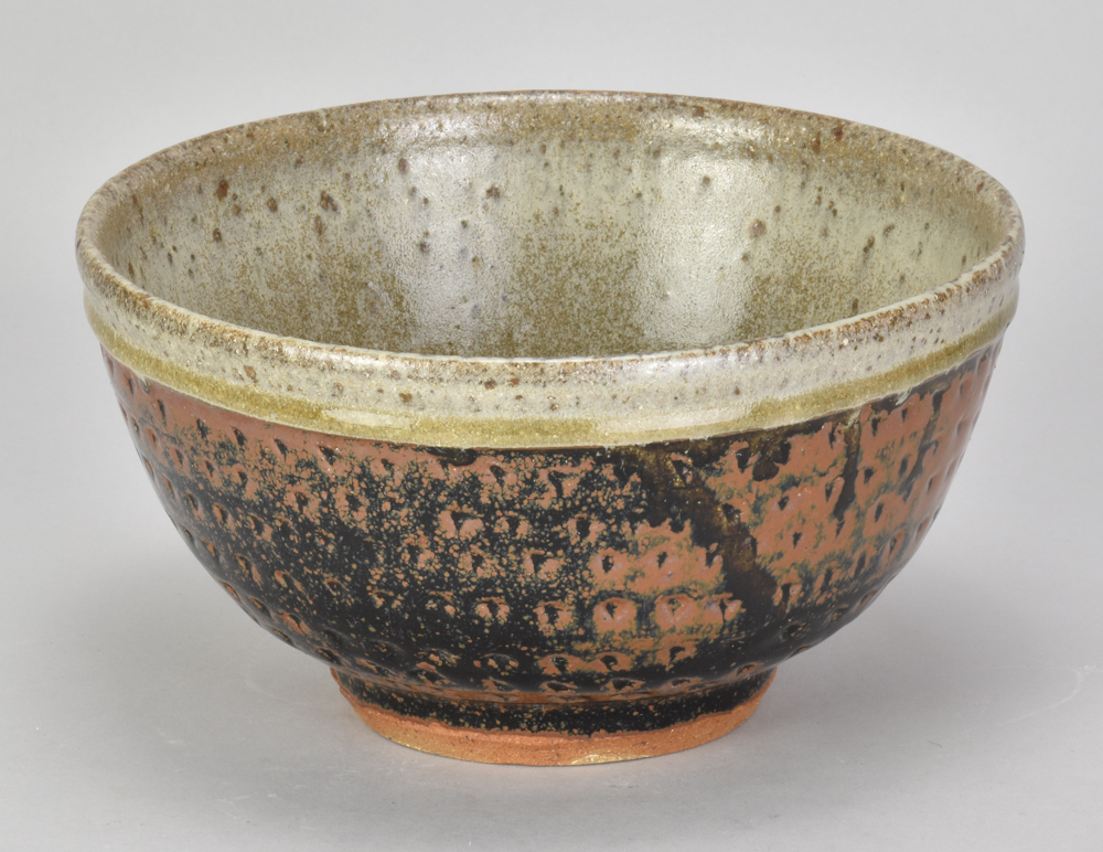 JIM MALONE (born 1946); a stoneware bowl covered in tenmoku breaking to kaki glaze with green ash